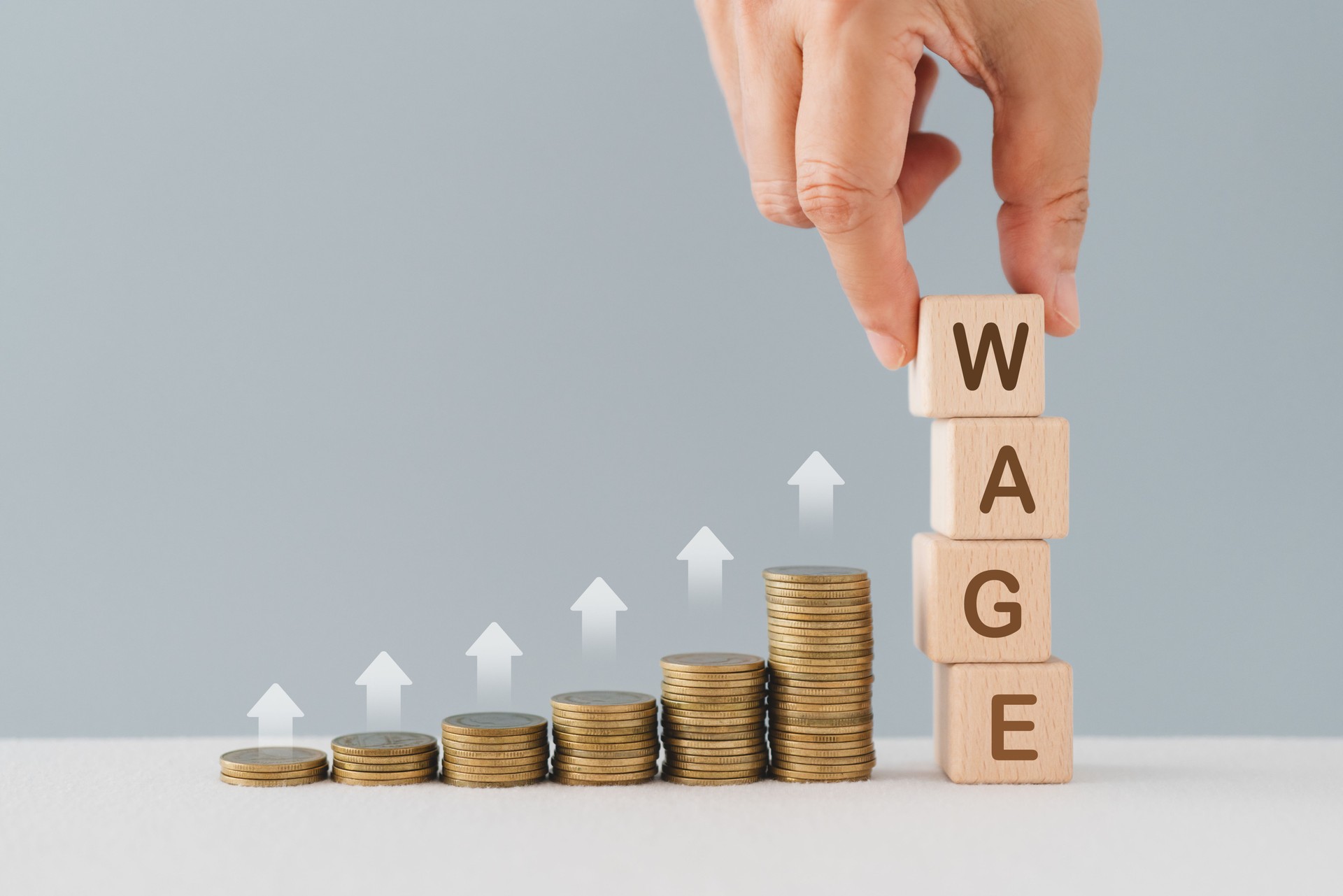 Wooden cube blocks with  word Wage, stack of coins and up arrow. Increase of salary. Wage rates. Career growth. Increase profits and family budget. Promotion. Growing career ladder